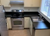 Thumbnail 9 of 16 - A kitchen with white cabinets and black countertops.