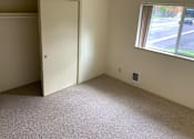 Thumbnail 14 of 16 - A room with a carpeted floor, a window, and a door.
