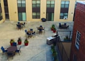 Thumbnail 17 of 30 - A courtyard with tables and chairs surrounded by buildings.