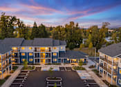 Thumbnail 1 of 10 - A large apartment complex with a parking lot in front.