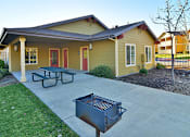 Thumbnail 7 of 41 - A yellow house with a red door and a picnic table in front.