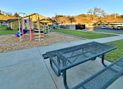 Thumbnail 11 of 41 - A playground with a slide and a picnic table.