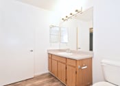 Thumbnail 14 of 30 - A white bathroom with a wooden cabinet and a white tub.