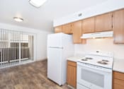 Thumbnail 16 of 30 - A white refrigerator in a kitchen with wooden cabinets.