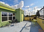 Thumbnail 5 of 29 - A patio with a table and chairs is surrounded by green walls.