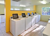 Thumbnail 12 of 30 - A laundromat with washers and dryers lined up.