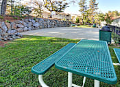 Thumbnail 7 of 30 - A green picnic table is in the foreground of a grassy area.