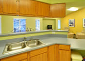 Thumbnail 11 of 30 - A kitchen with a sink and wooden cabinets.