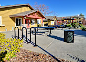 Thumbnail 7 of 17 - A yellow building with a red door and a black trash can in front of it.