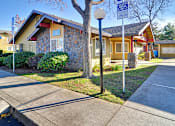 Thumbnail 4 of 17 - A house with a stone wall and a tree in front.