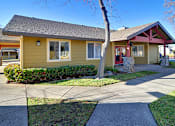 Thumbnail 6 of 17 - A yellow house with a red trim and a stone pillar in front.