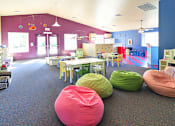 Thumbnail 12 of 17 - A room with a purple wall and a carpeted floor with bean bag chairs.