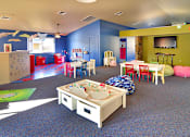 Thumbnail 5 of 17 - A playroom with a blue carpet and a white table.