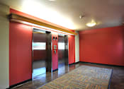 Thumbnail 5 of 30 - Two elevators in a hallway with red walls.