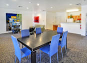 Thumbnail 21 of 41 - A black dining table with blue chairs in a room.