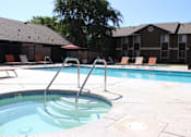 Thumbnail 6 of 16 - A hot tub sits in the middle of a pool surrounded by chairs.