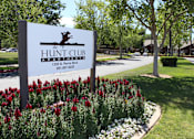 Thumbnail 4 of 16 - A sign for The Hunt Club Apartments stands in front of a flower bed.