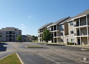 Thumbnail 5 of 11 - A sunny day at a residential complex with apartment buildings on either side of a central road.