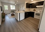 Thumbnail 5 of 10 - A kitchen with black cabinets and white appliances.
