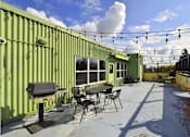 Thumbnail 6 of 29 - A patio with a table and chairs is set up on a rooftop.