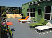 Thumbnail 11 of 29 - A patio with a green building and white furniture.