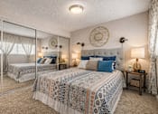 Thumbnail 24 of 25 - A bedroom with two beds and a mirror. at Infinity on the Landing Apartments , Texas