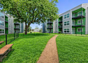 Thumbnail 8 of 25 - A tree in a grassy area in front of apartment buildings. at Infinity on the Landing Apartments , Euless, TX, 76040