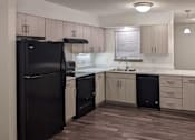 Thumbnail 64 of 74 - A black refrigerator is in a kitchen with wooden floors and white walls.