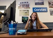 Thumbnail 1 of 37 - A woman is talking on the phone in an office with a Corvias logo on the wall.