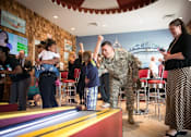 Thumbnail 2 of 37 - A man in a military uniform is playing a game of bowling with a young girl.