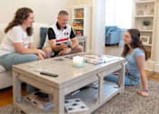 Thumbnail 3 of 37 - Three people are sitting around a coffee table playing a game.