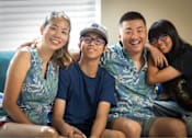 Thumbnail 13 of 37 - A group of four people wearing matching blue shirts with a pattern of white birds and green leaves.