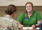 Thumbnail 15 of 37 - A woman in a green shirt is sitting at a table with a woman in a camouflage shirt.