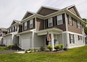 Thumbnail 30 of 37 - A house with a brown and grey exterior and a flag on the front porch.