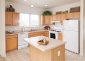 Thumbnail 33 of 37 - A kitchen with wooden cabinets and white appliances.