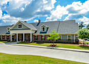 Thumbnail 43 of 74 - A large house with a grey roof and a green lawn in front.