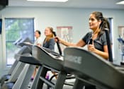 Thumbnail 31 of 74 - A woman is working out on a treadmill in a gym.