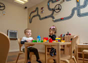 Thumbnail 9 of 21 - Two children playing with toys in a playroom.