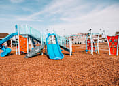 Thumbnail 2 of 21 - A playground with a blue slide and orange and grey climbing structures.