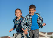 Thumbnail 14 of 21 - Two children are running in a grassy field.