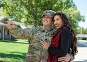 Thumbnail 21 of 21 - A man in military uniform points at something while standing next to a woman.