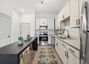Thumbnail 54 of 69 - A kitchen with a black countertop and stainless steel appliances.