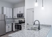 Thumbnail 25 of 69 - A kitchen with a granite countertop and stainless steel appliances.