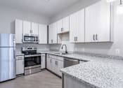 Thumbnail 23 of 69 - A kitchen with white cabinets and stainless steel appliances.