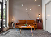 Thumbnail 43 of 69 - A living room with a brown leather couch and a wooden coffee table.