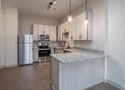 Thumbnail 24 of 69 - A kitchen with a stainless steel refrigerator, microwave, oven, and sink.