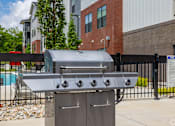 Thumbnail 42 of 69 - A silver gas grill with four burners is in front of a black fence.