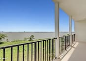 Thumbnail 13 of 25 - A balcony with a view of a body of water and trees.