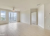 Thumbnail 20 of 25 - A spacious room with a ceiling fan and sliding glass doors leading to a balcony.