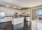 Thumbnail 15 of 25 - A kitchen with white cabinets and black countertops.